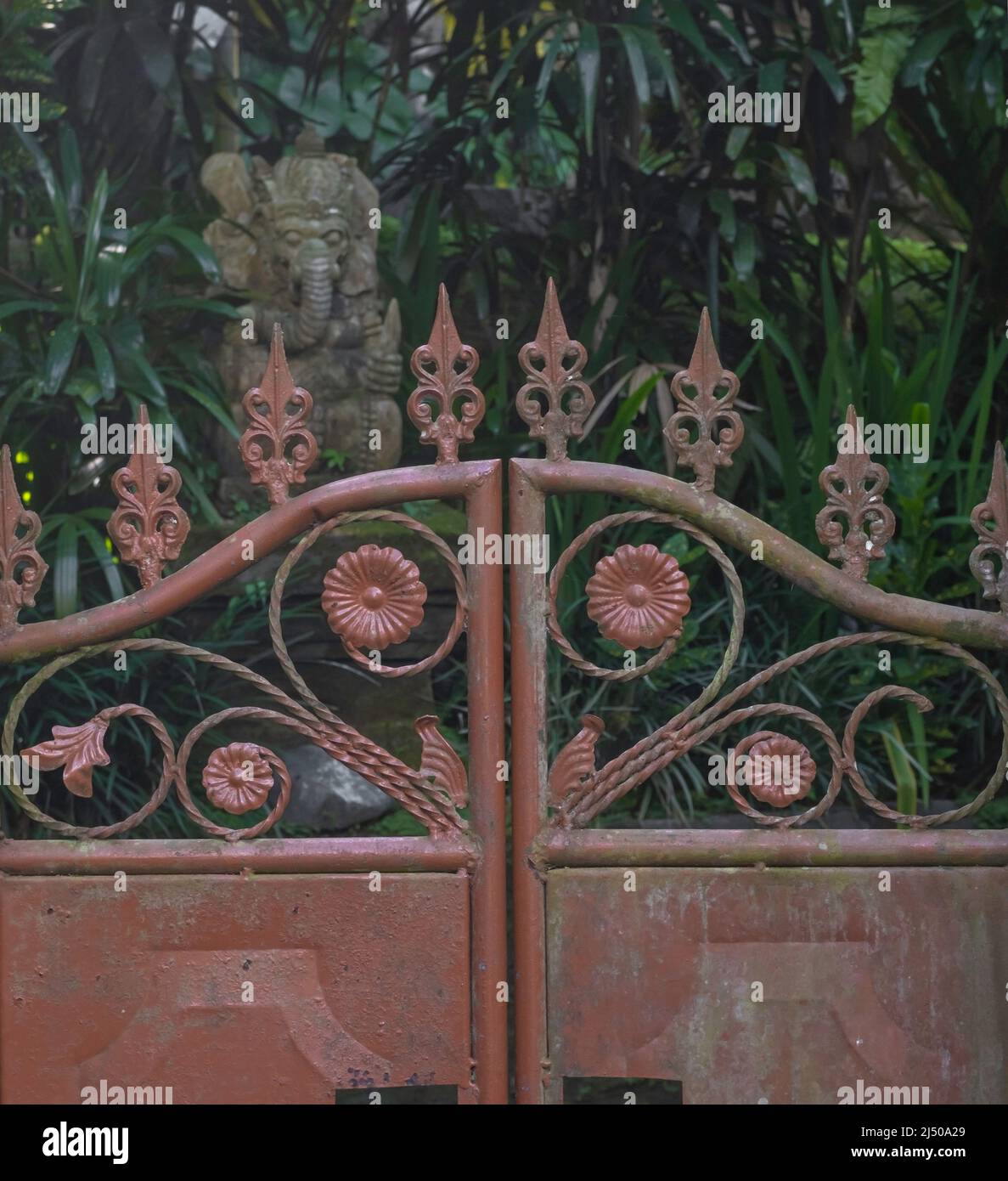 Old red iron gate with flower emblems and blurred background with