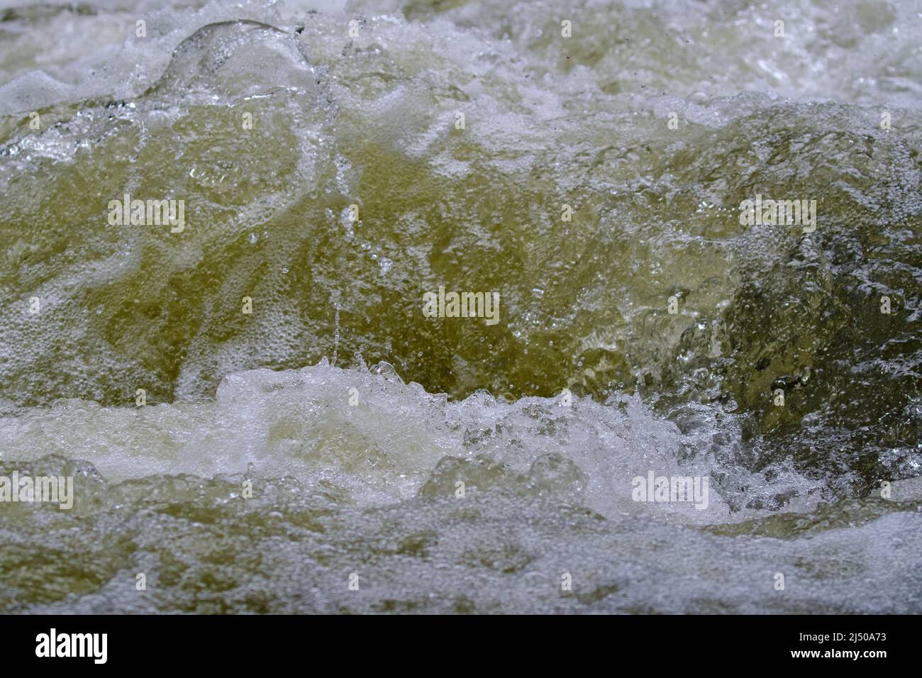 Texture of water in a natural state, in a river when splashing against the stones. Stock Photo