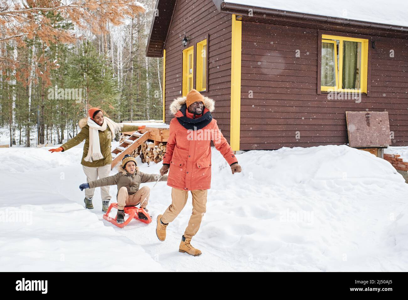 Young cheerful black man having fun with his family while pulling ...