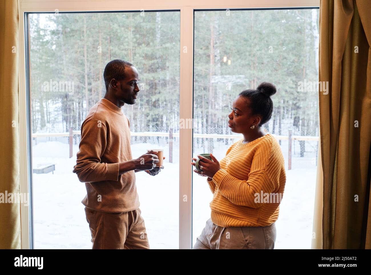 Side view of young African American couple in casualwear having tea ...