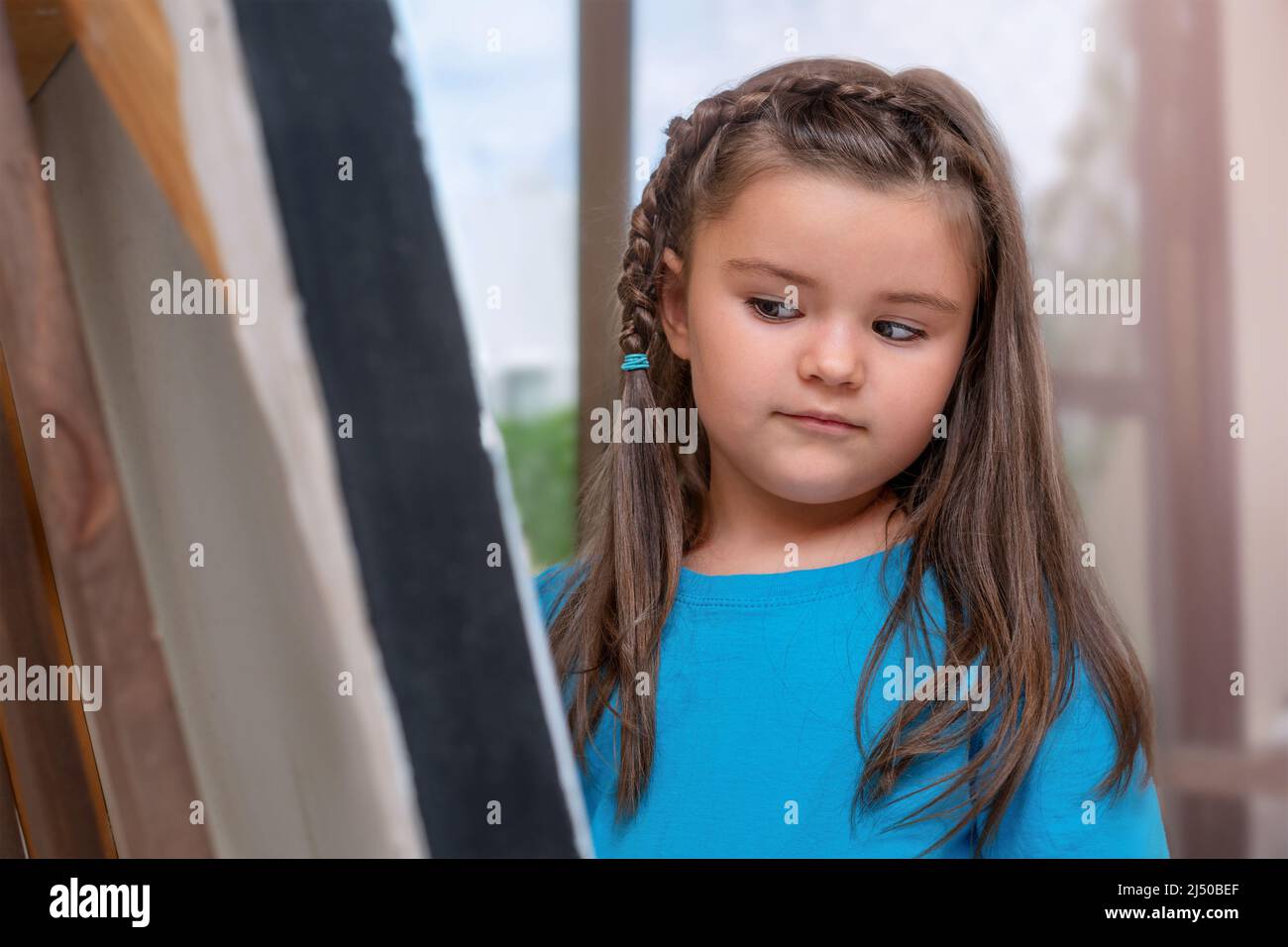 Child girl looks at an easel with a picture Stock Photo - Alamy
