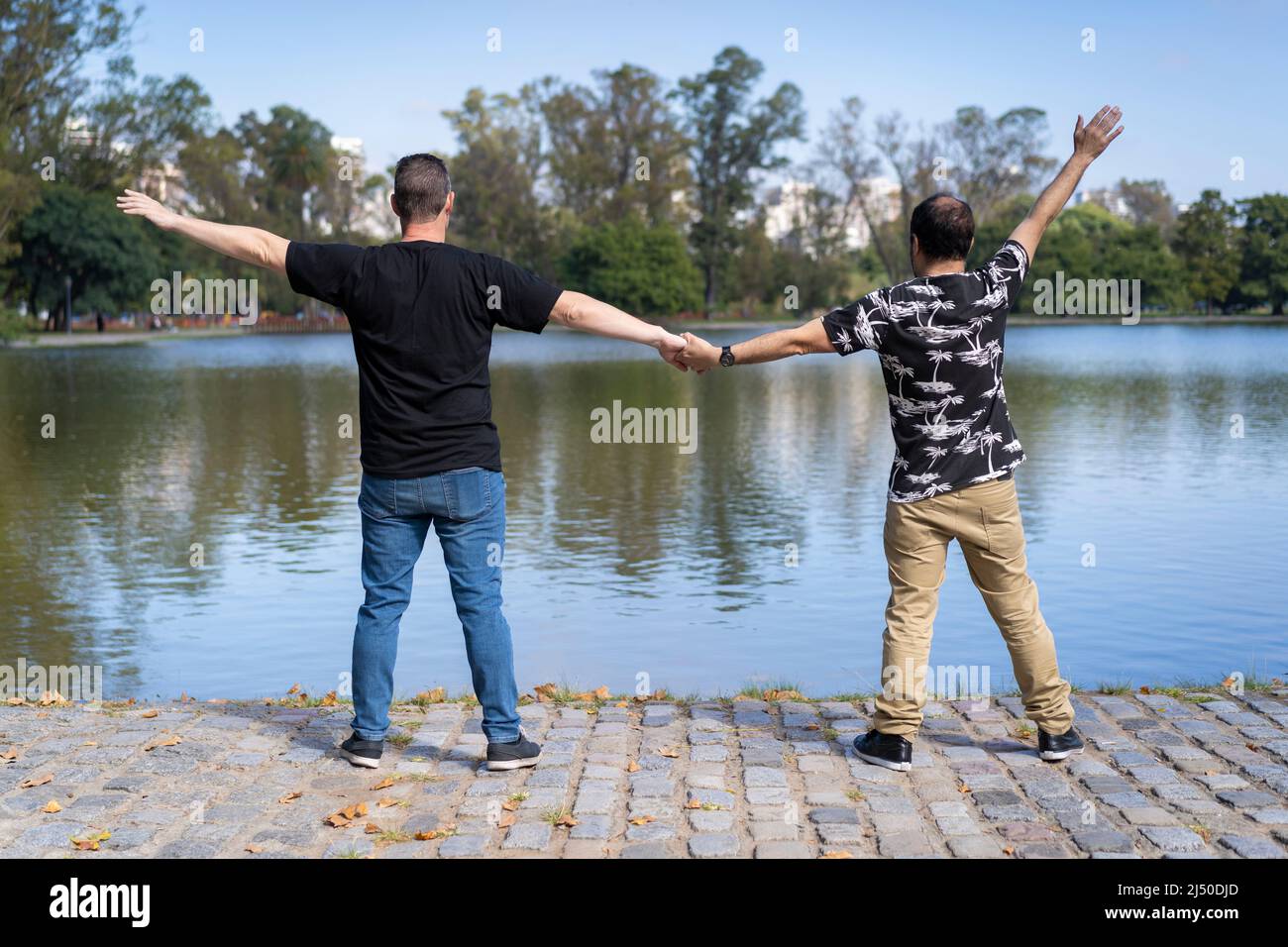 A mature white men couple holding hands and facing a lake Stock Photo