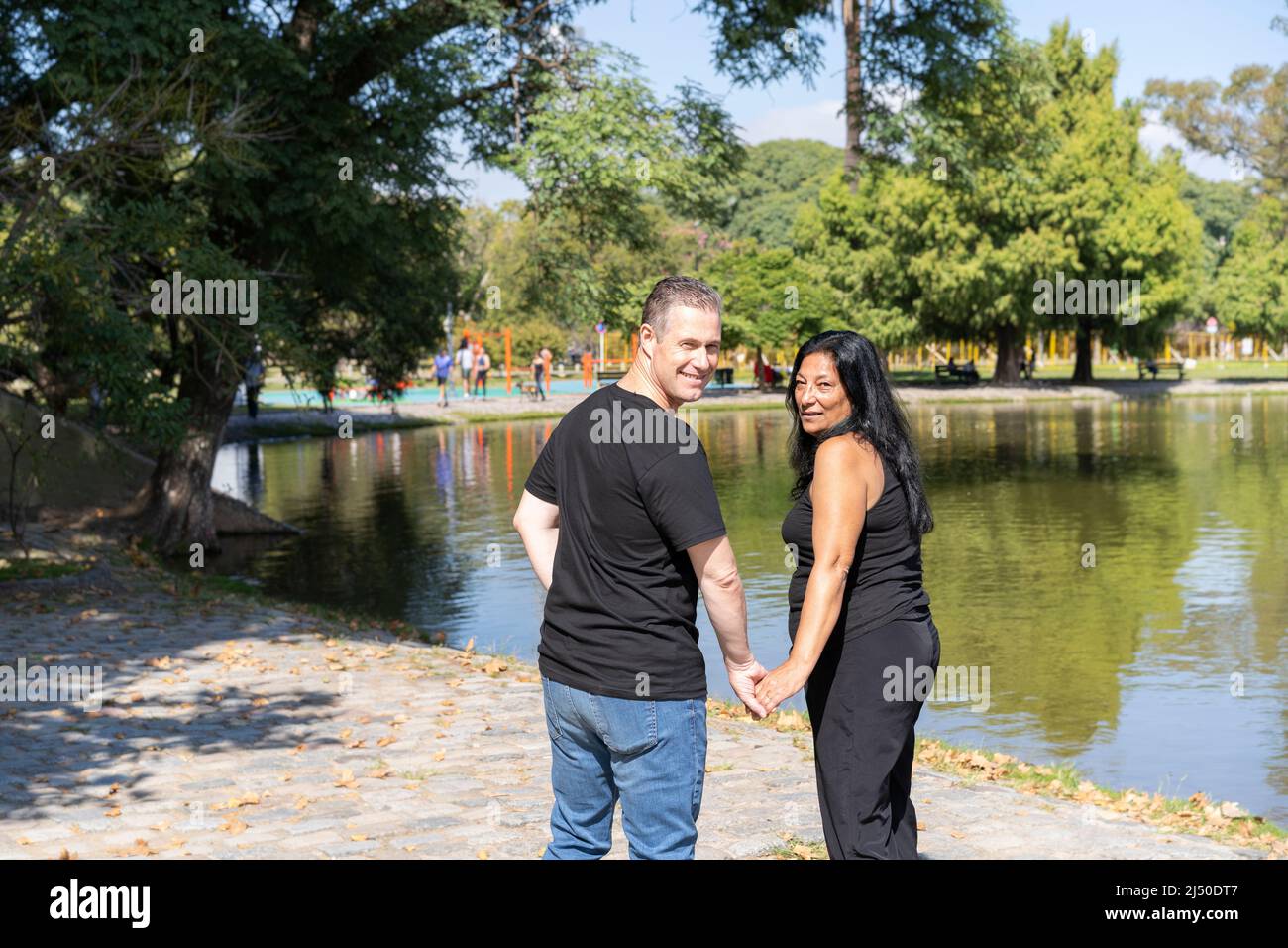 Multi-ethnic couple formed by an Andean woman and a Caucasian man walking by a lake. Happy expressions and faces of lovers Stock Photo