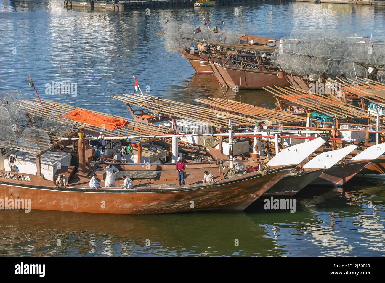 The crew of a traditional fishing dhow, laden with gargours or fish traps, fishing near Sharjah Bridge in Sharjah in the United Arab Emirates. Stock Photo