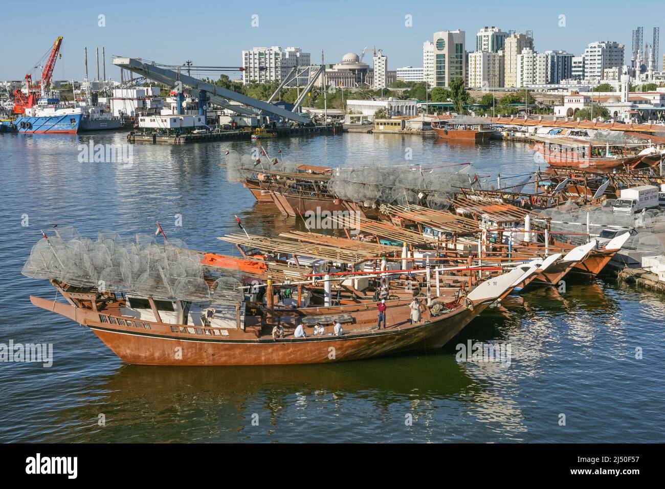The crew of a traditional fishing dhow, laden with gargours or fish traps, fishing near Sharjah Bridge in Sharjah in the United Arab Emirates. Stock Photo