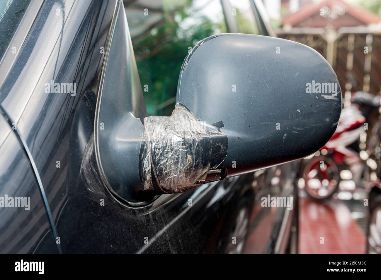 The side mirror of the black car was broken and fix with adhesive tape