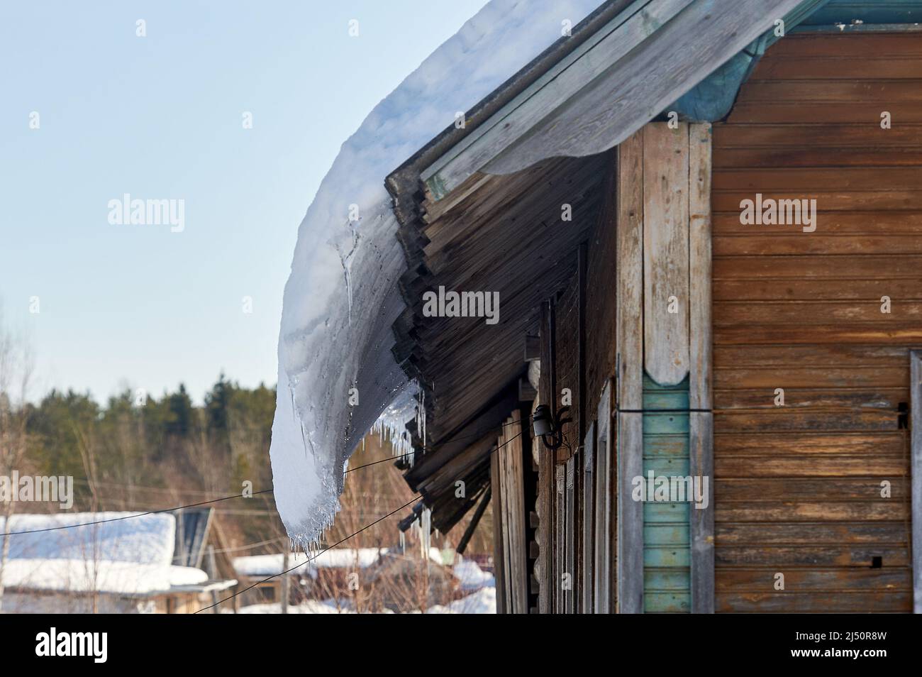 a block of ice hangs from the roof of the house Stock Photo
