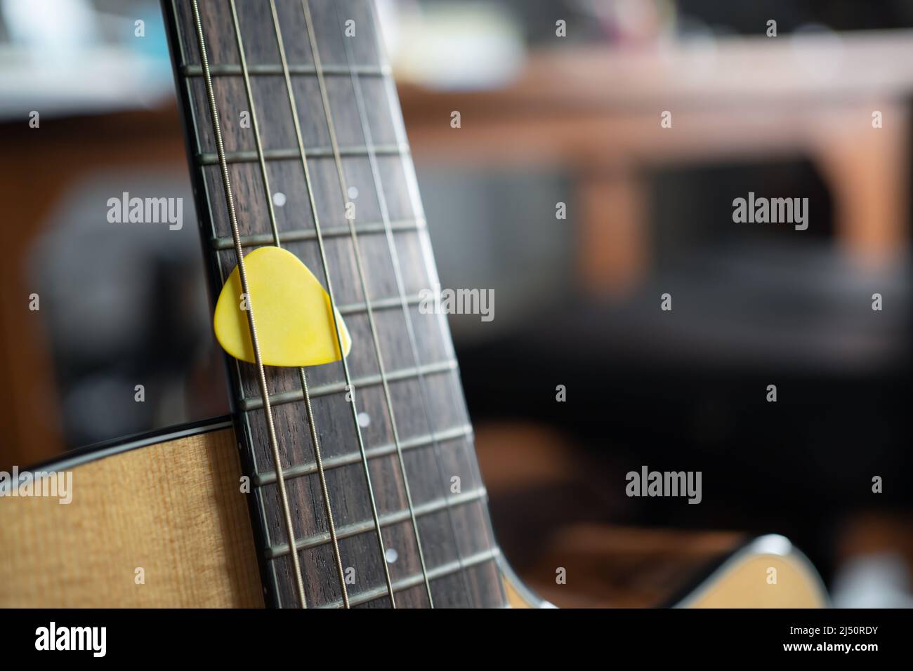 Yellow guitar pick on an acoustic guitar Stock Photo