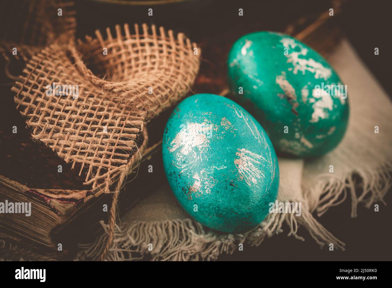Two green and turquoise metallic Easter eggs with an antique book on a ...