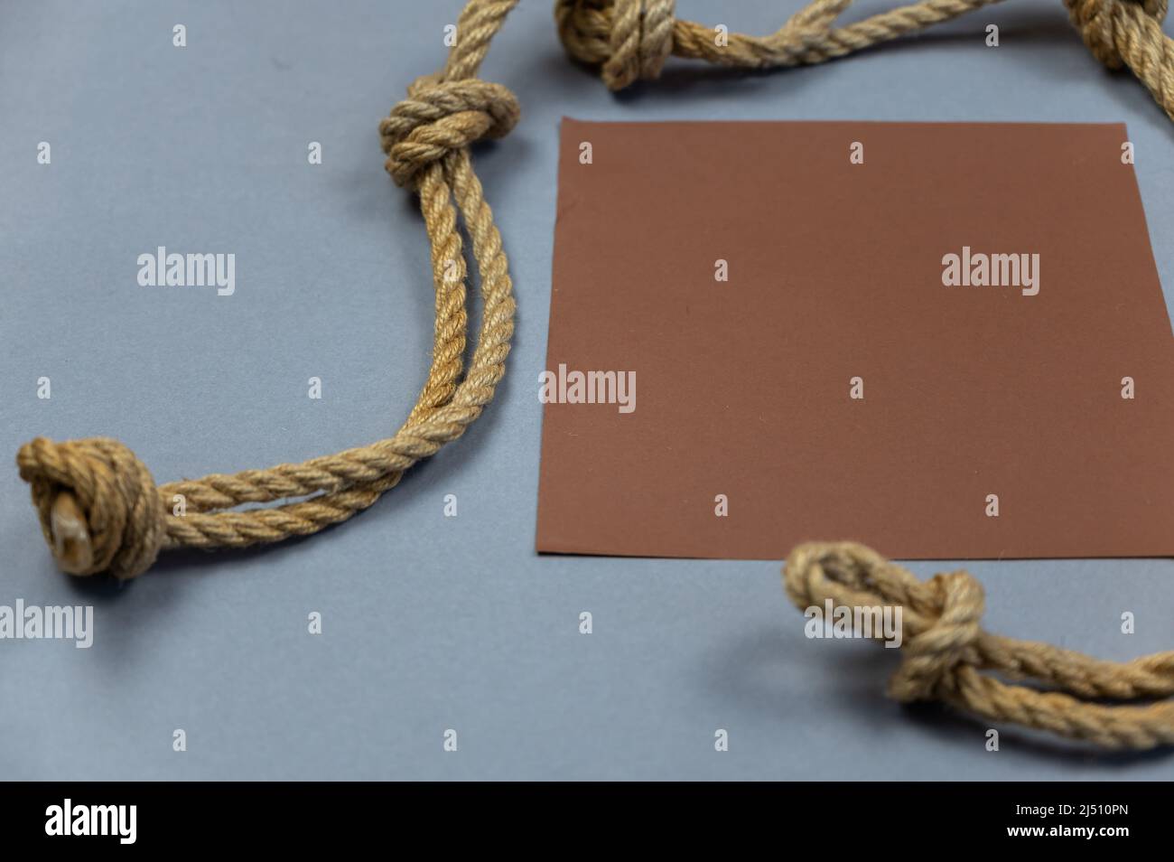 A ship's rope with knots and a brown empty square against a gray ...