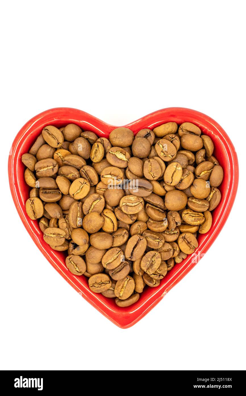 Coffee beans isolated on a white background. Full of coffee beans in a heart shaped plate. Close-up. Top view. Stock Photo