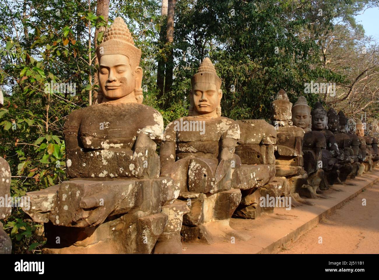 Ancient devas statues carved out of stones depicting the scene of Samudra Manthan (Devas Pulling Vasuki) at the  gate of Angkor Thom, Siem Reap, Cambo Stock Photo