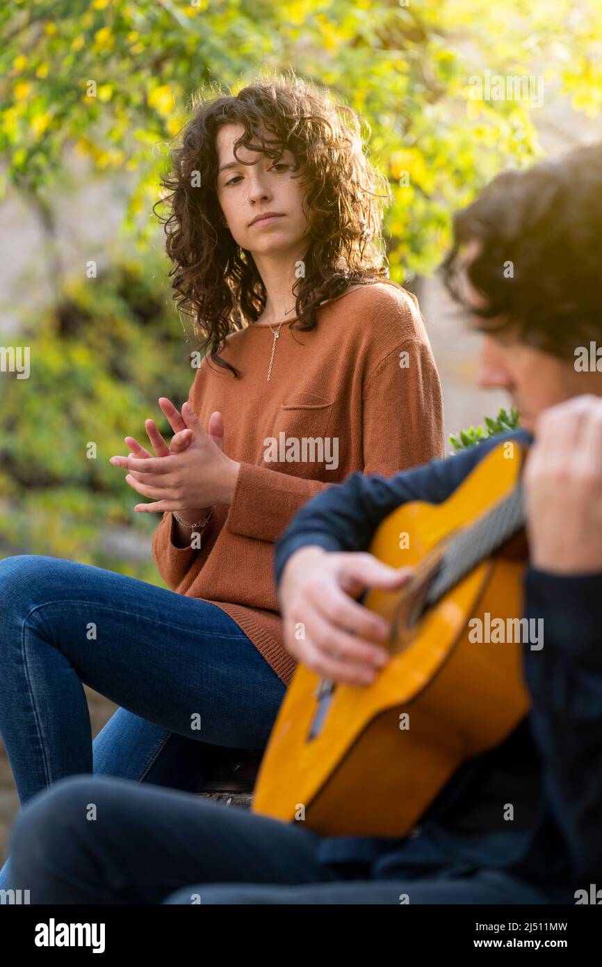 Young curly woman singing with a guitarist man in the street Stock Photo