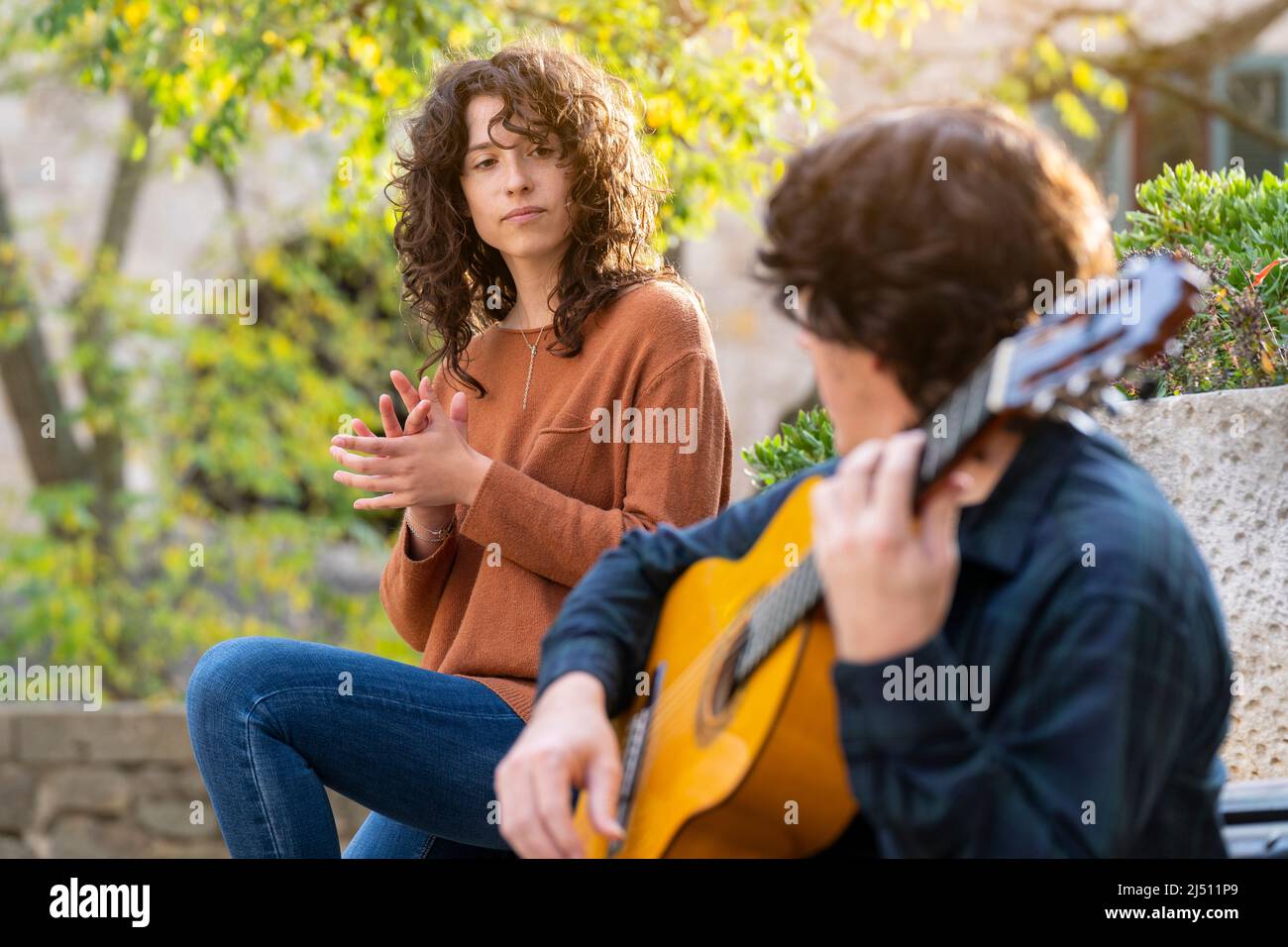 Young curly woman singing with a guitarist man in the street Stock Photo