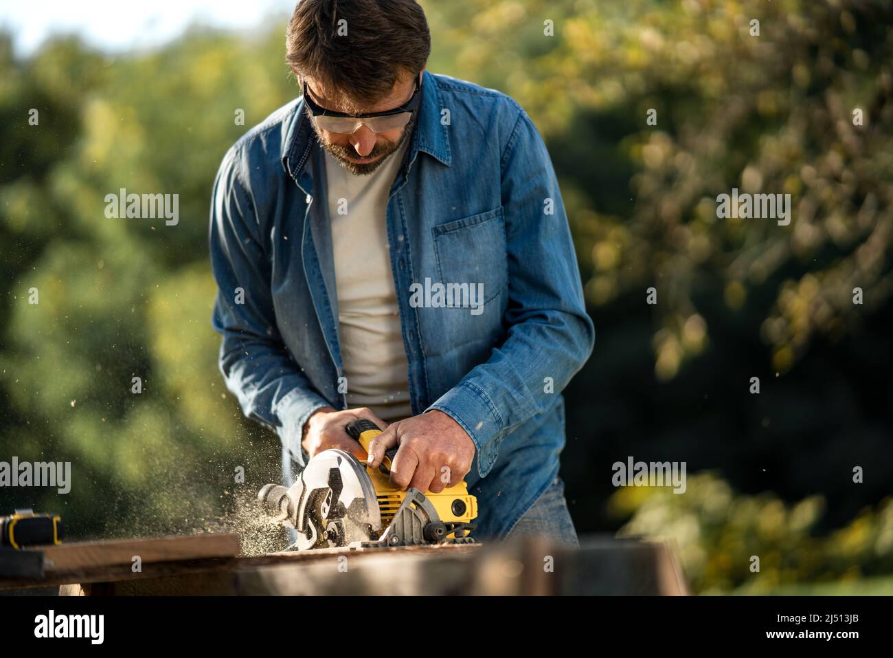Craftsman working with circular saw at construction site Stock Photo