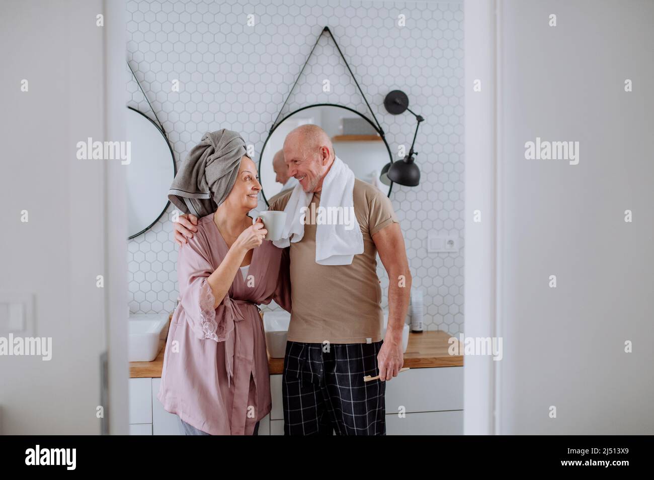 Senior couple in love in bathroom, brushing teeth and talking, morning routine concept. Stock Photo