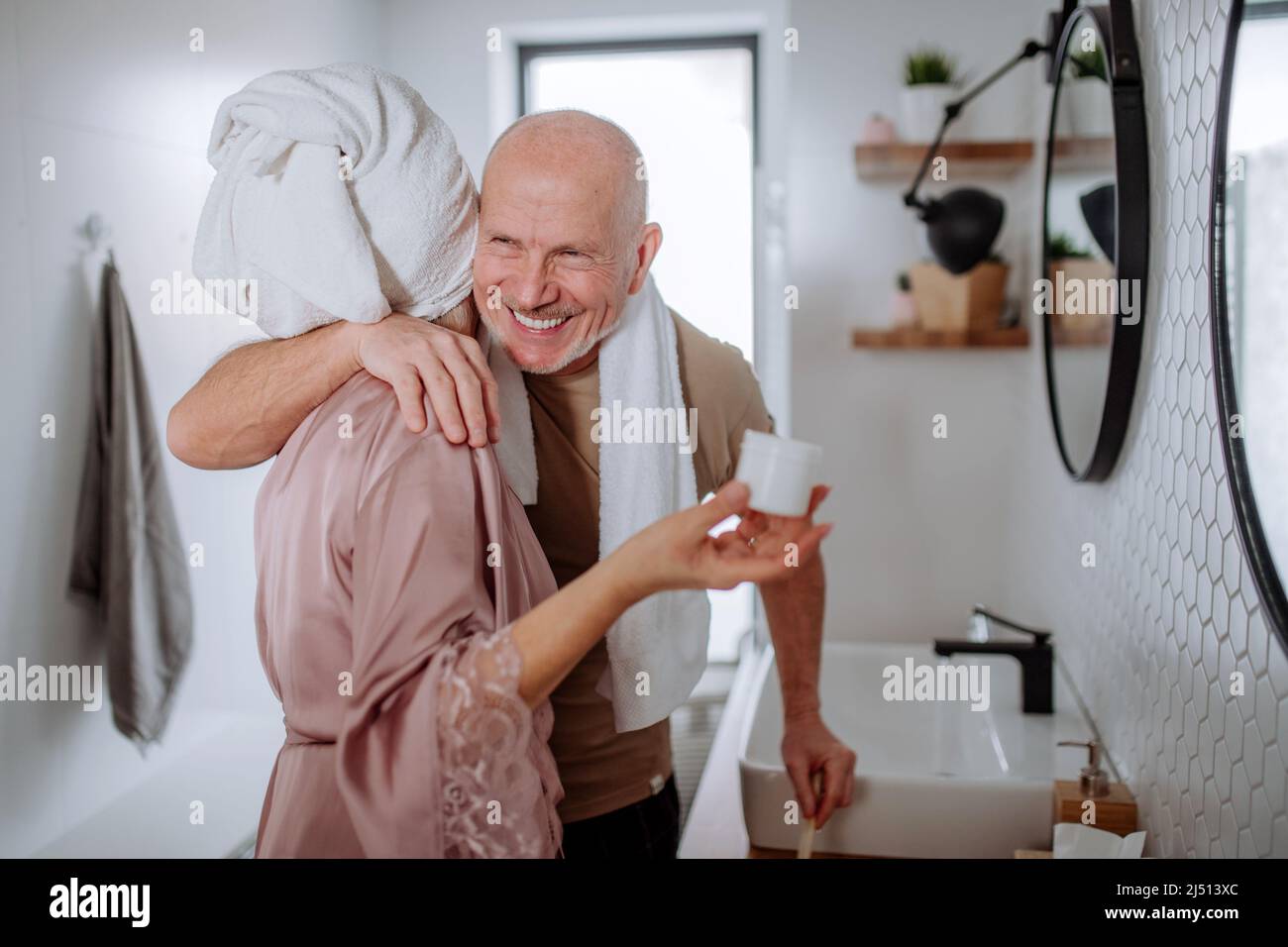 Senior couple in love in bathroom, brushing teeth and hugging, morning routine concept. Stock Photo