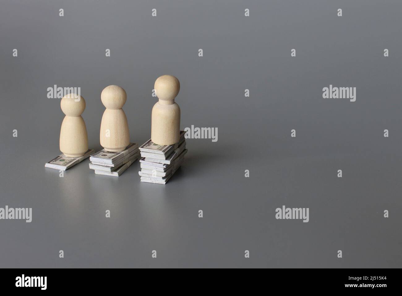 Wooden dolls and stack of money with copy space for text. Pay gap, wage gap concept. Stock Photo