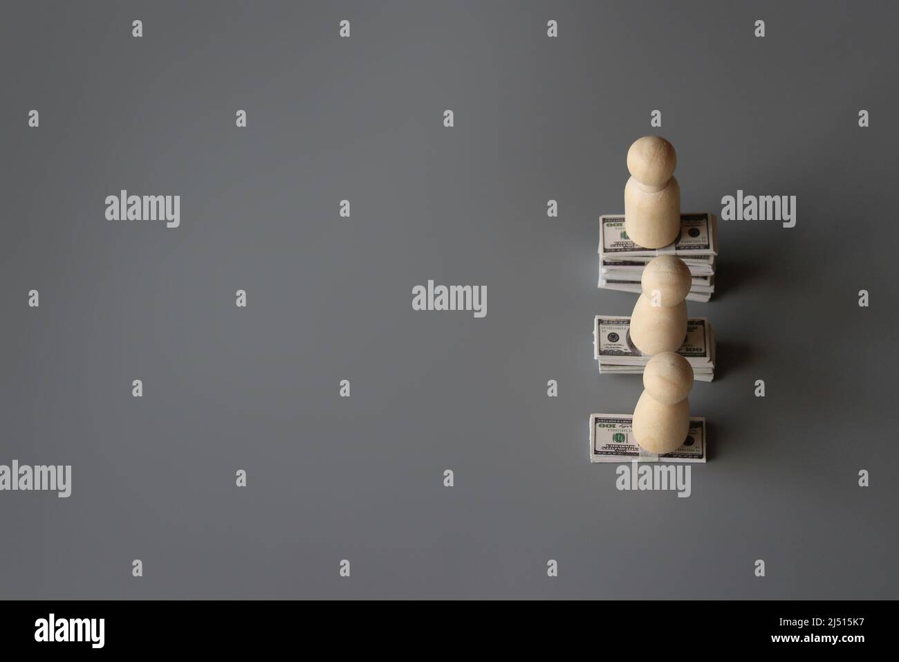 Wooden dolls and stack of money with copy space for text. Pay gap, wage gap concept. Stock Photo