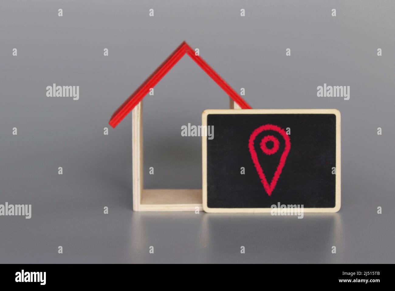 Toy house and red pin location. Search for housing options, tracking, navigation and relocation. Stock Photo