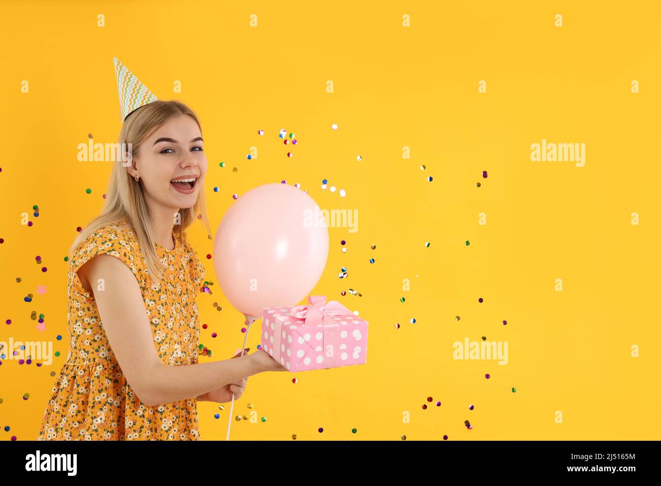 Concept of Happy Birthday, young woman on yellow background Stock Photo