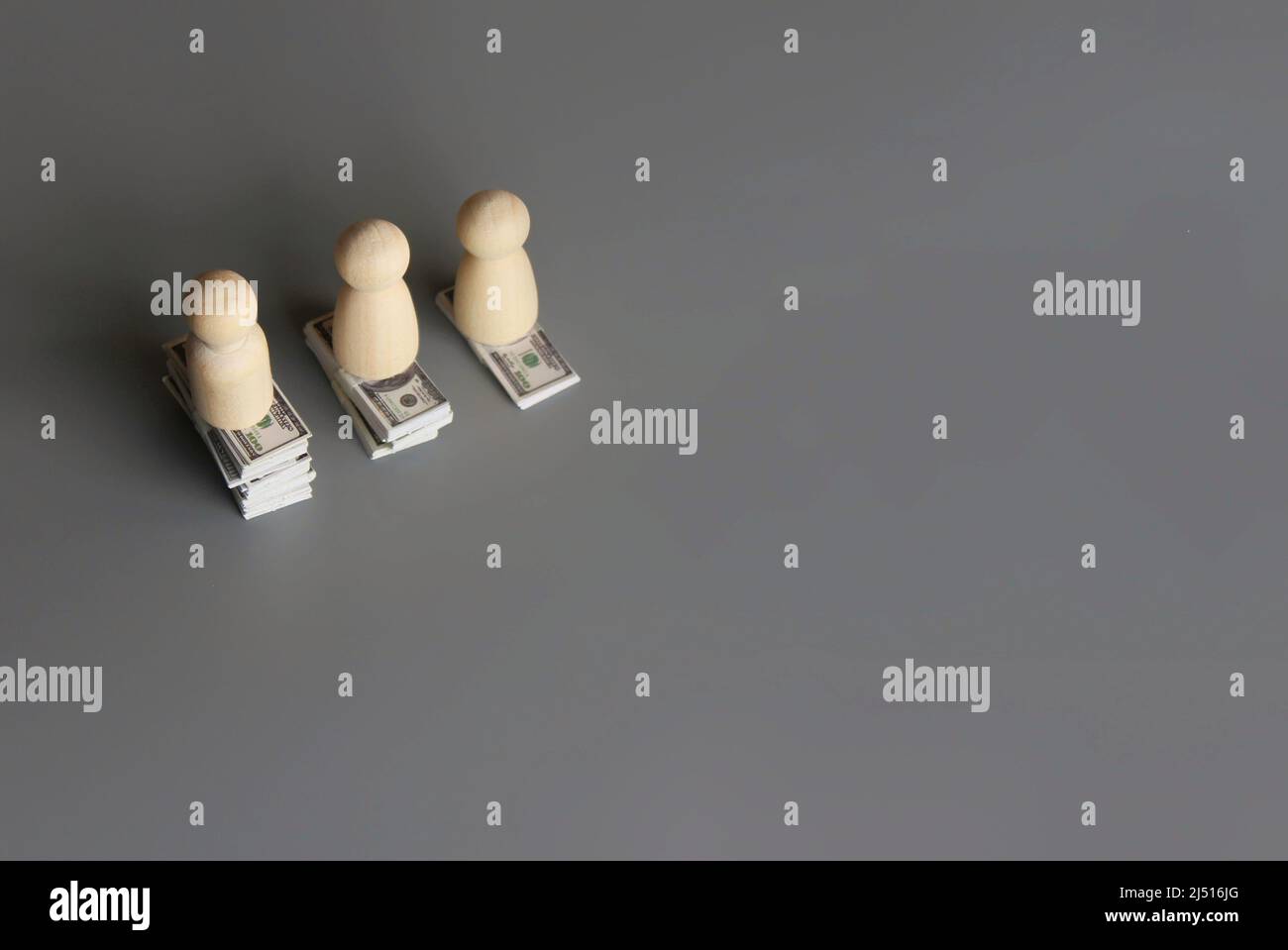 Wooden dolls and stack of money with copy space for text. Pay gap, wage gap concept. Stock Photo