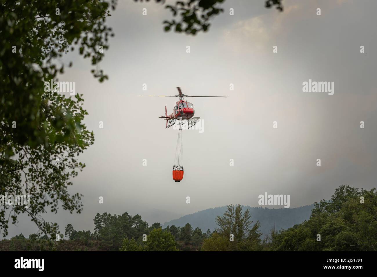 Firefighting helicopter carries bucket of water to extinguish forest