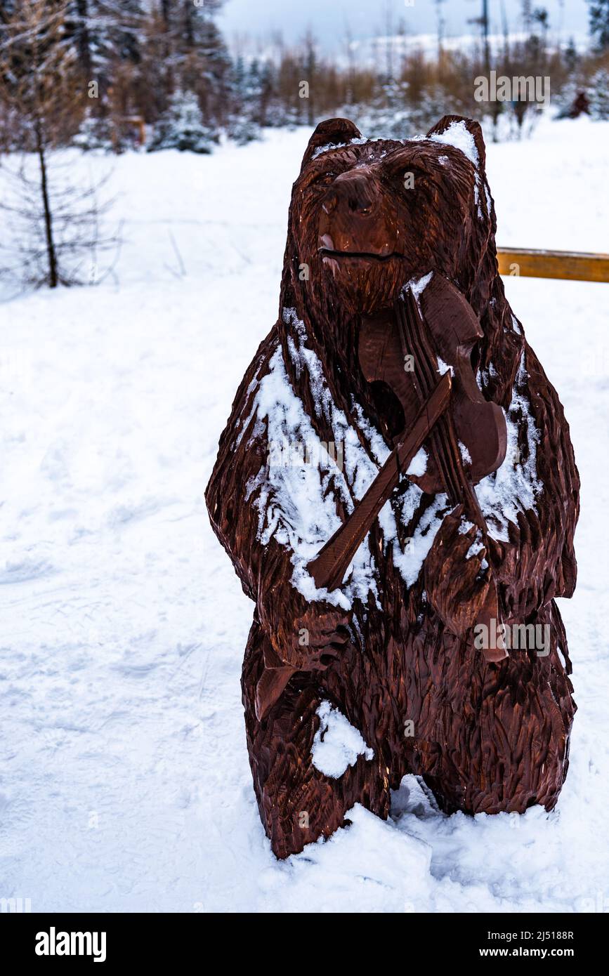 Wooden bear in winter playing musical instrument Stock Photo