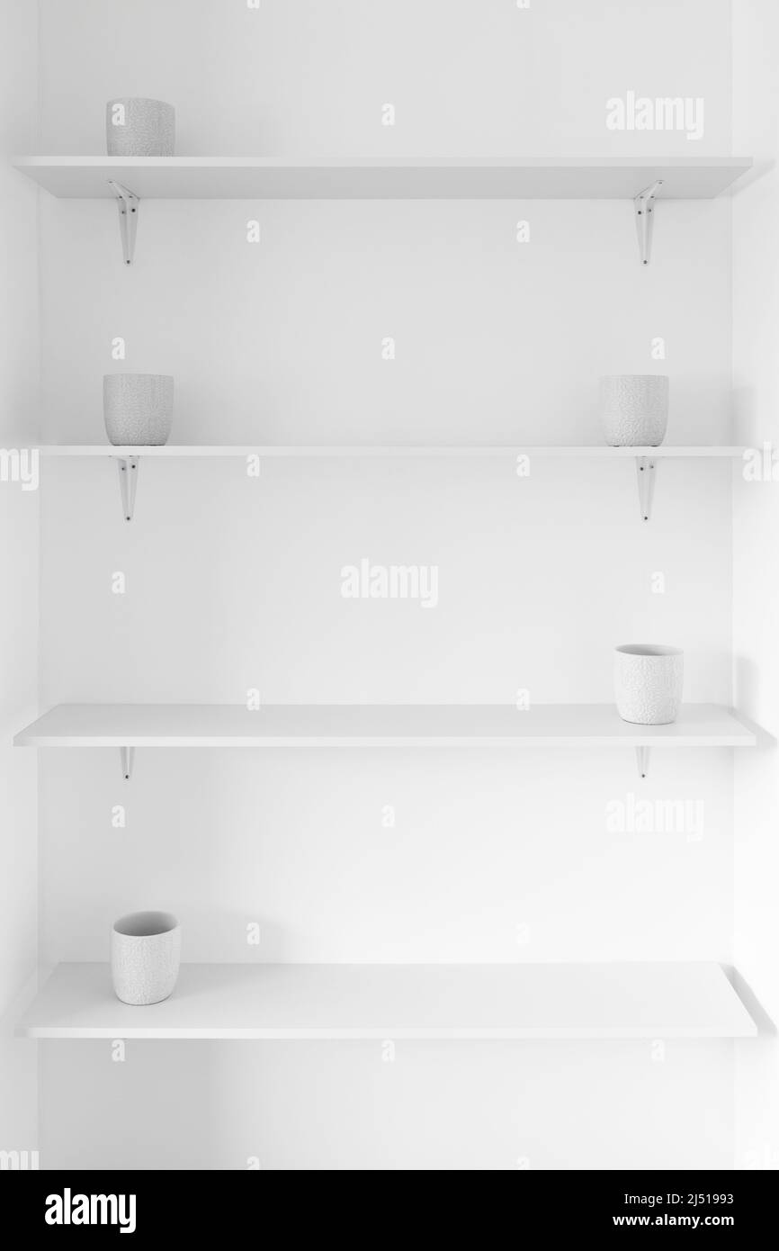 minimalist white wall with shelves in a niche and white plant pots, concept of modern interior