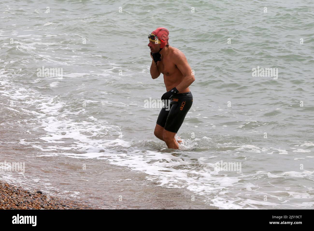 Brighton. UK 18 Apr 2022 - A swimmer returns after his swim in the sea on the Brighton seafront as the mini-heatwave is set to end with light showers and temperatures of around 13 degrees Celsius. Credit Dinendra Haria /Alamy Live News Stock Photo