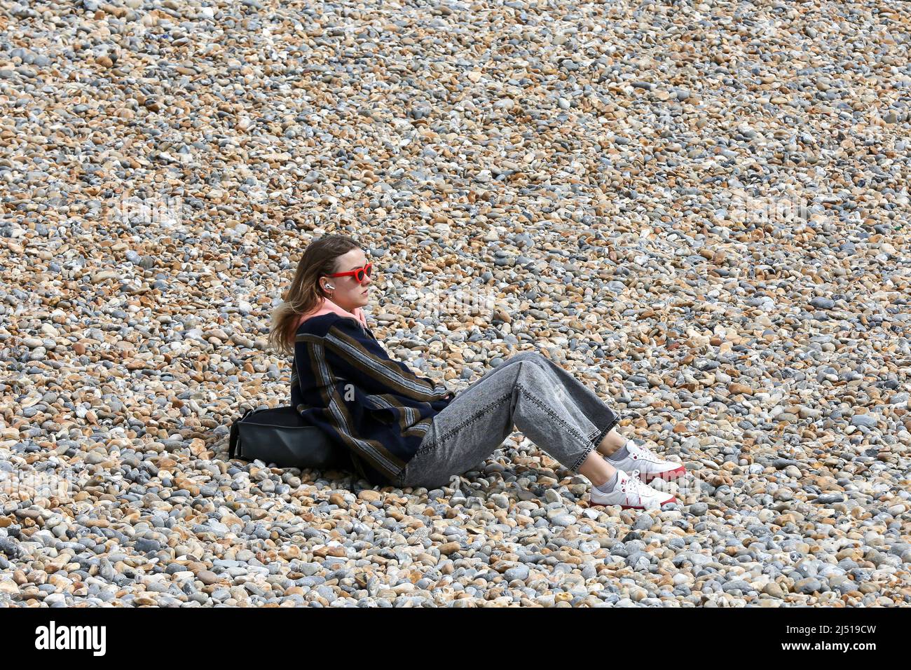 Brighton. UK 18 Apr 2022 - A sun-seeker enjoy Easter Monday on the Brighton seafront as the mini-heatwave is set to end with light showers and temperatures of around 13 degrees Celsius. Credit Dinendra Haria /Alamy Live News Stock Photo