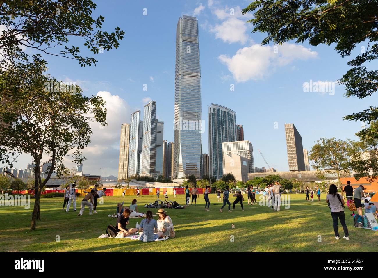 15 5 2021 people chat and play on grass before International Commerce Centre (ICC) building in Tsim Sha Tsui, Kowloon Peninsula, seen in West Kowloon Stock Photo