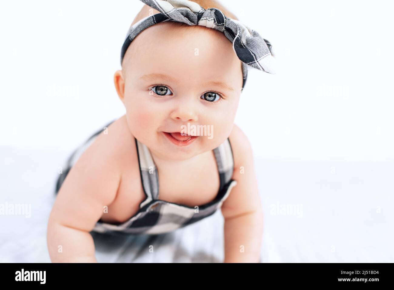 Seven month old baby child sitting on bed. Cute smiling little infant