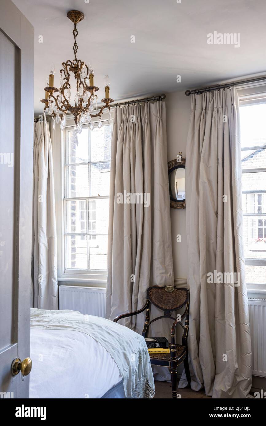 Silk curtains and French 1930s crystal chandelier in Grade II listed 1820s London cottage, UK Stock Photo