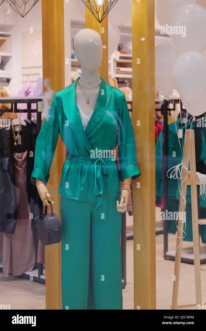 Mannequins in the big shopping shop. Female mannequin in green casual clothes stand in a clothing store. Stock Photo