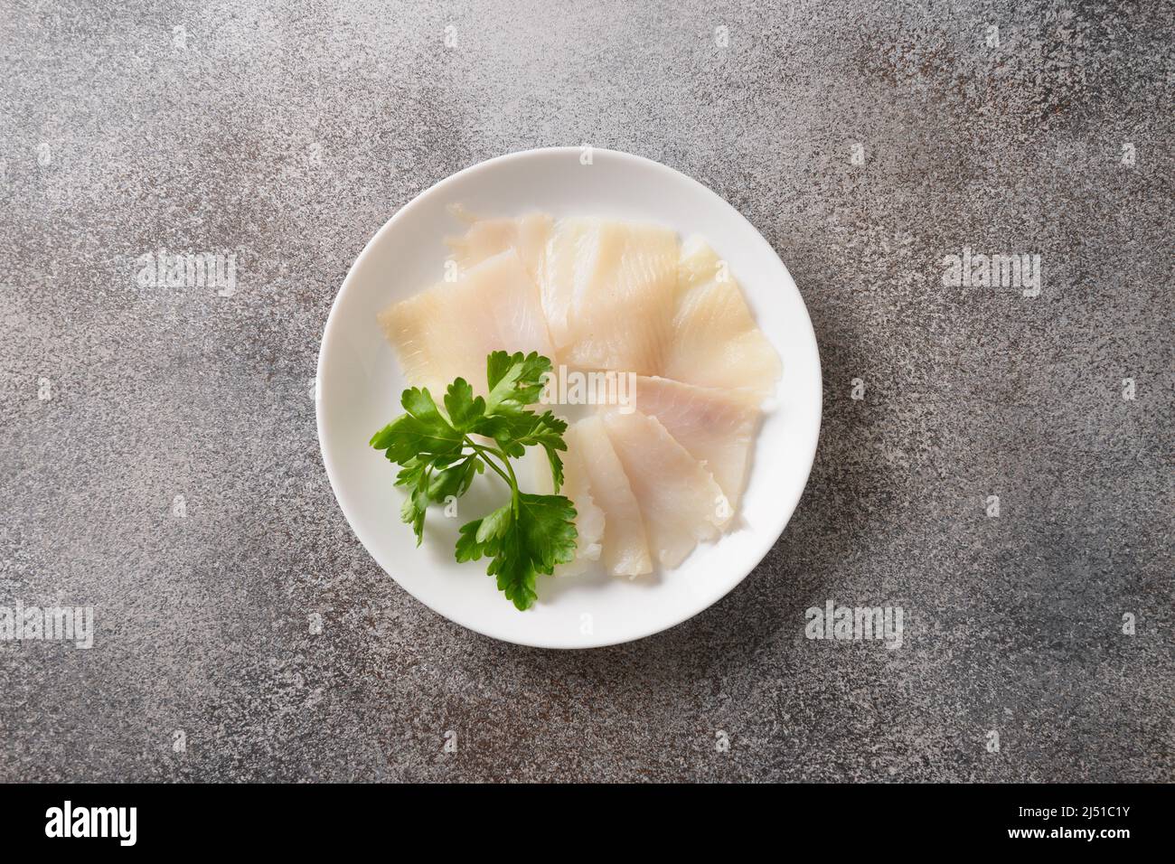 Delicious smoked halibut slices served in white plate isolated on gray background. View from above. Stock Photo