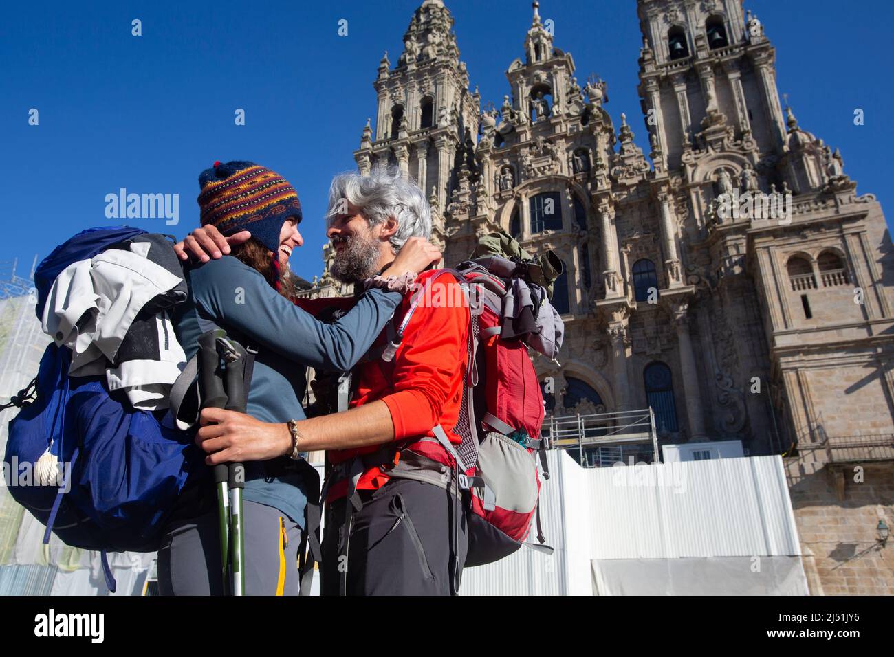 A couple of pilgrims celebrate in front of the cathedral of Santiago that they have reached the end of the journey after walking the Camino de Santiag Stock Photo