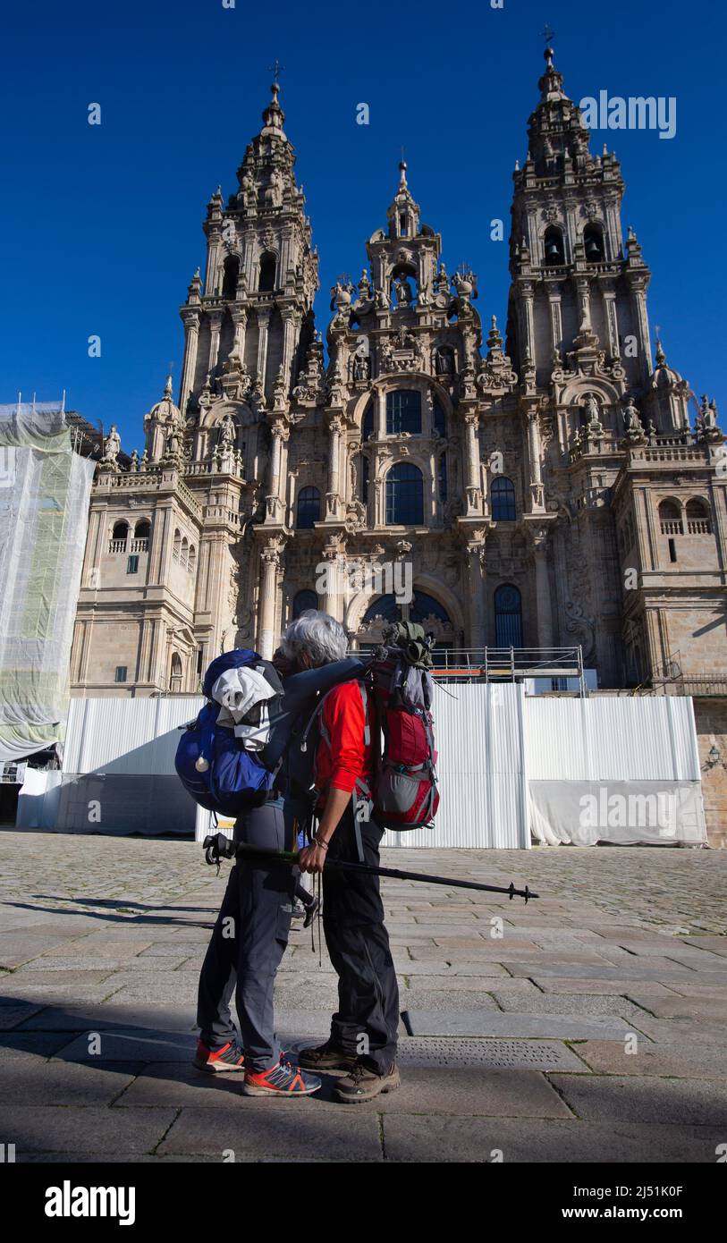 A couple of pilgrims celebrate in front of the cathedral of Santiago that they have reached the end of the journey after walking the Camino de Santiag Stock Photo