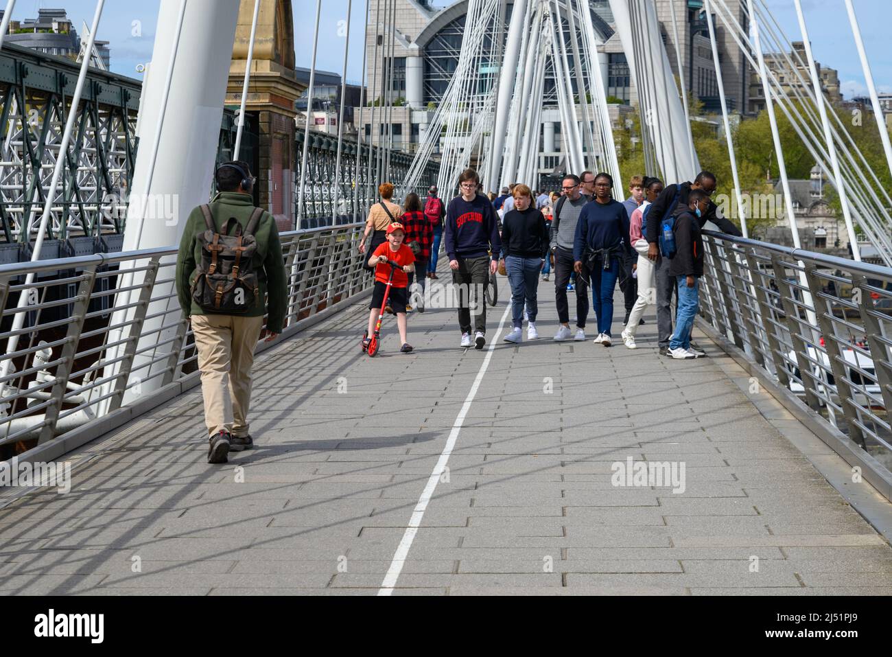 People walking across Golden Jubilee Bridge, London, UK, April Stock Photo