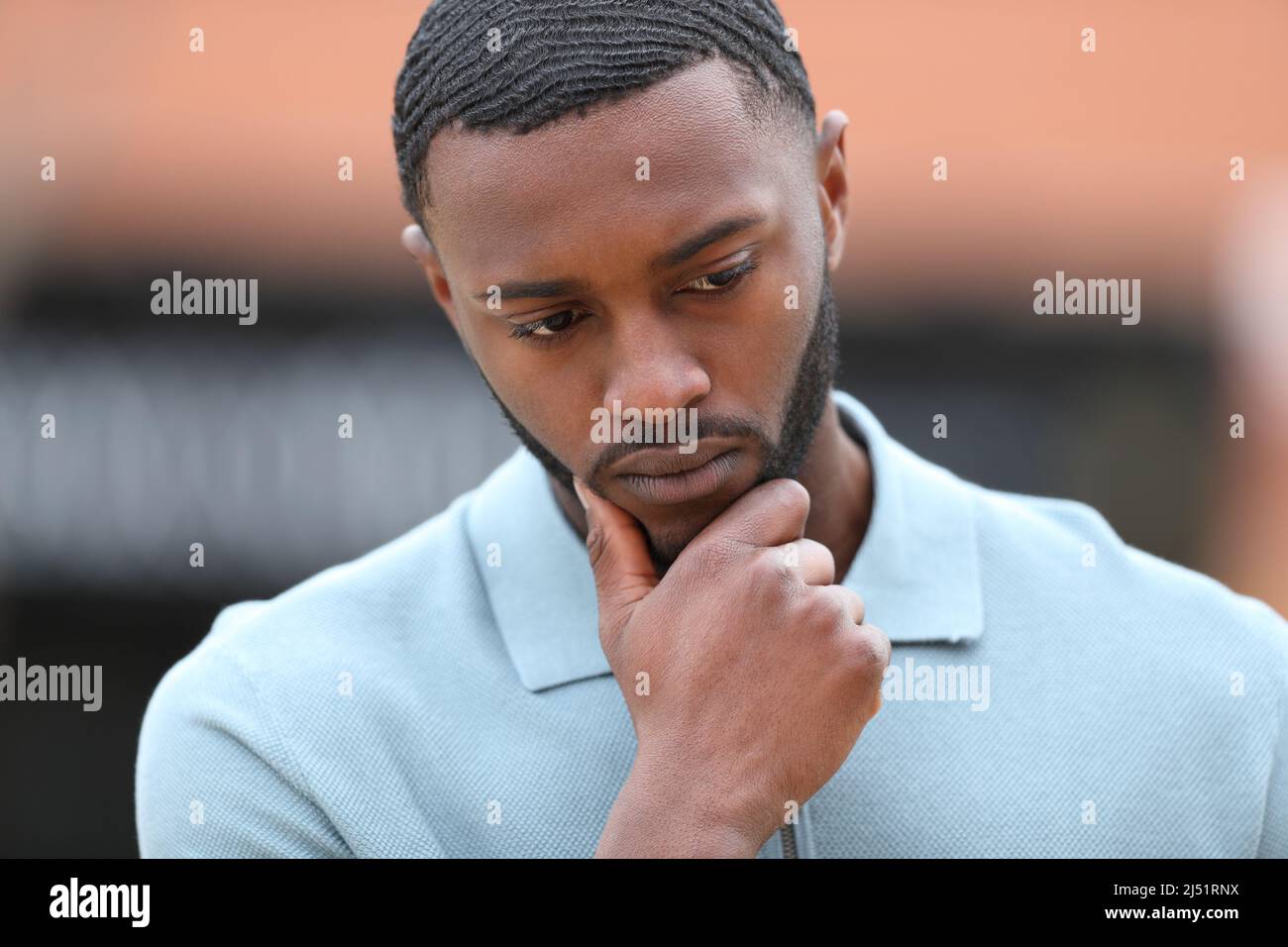 Front view portrait of a worried man with black skin thinking in the street Stock Photo