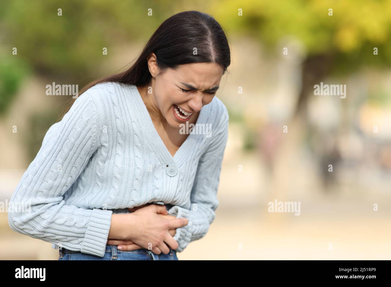 Woman crying suffering belly ache complaining in the street Stock Photo