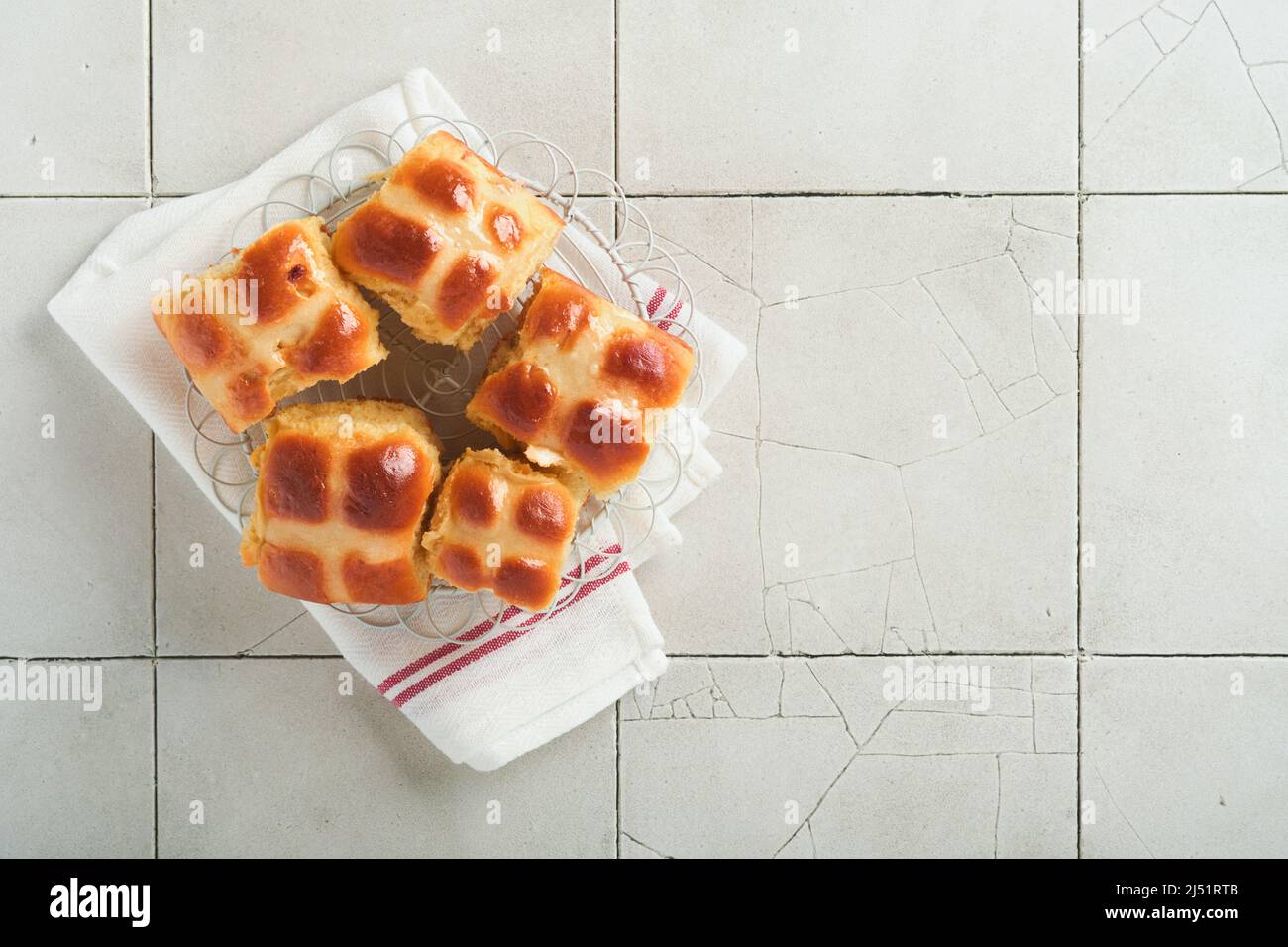Easter hot cross buns with colored eggs Easter gingerbread rabbits and cookies over light grey old cracked tile table background. Spring holiday bakin Stock Photo
