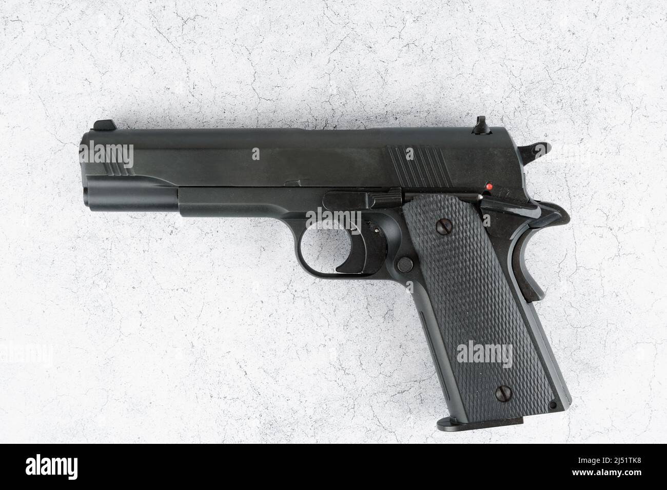 Black semi-automatic pistol on concrete backdrop Stock Photo