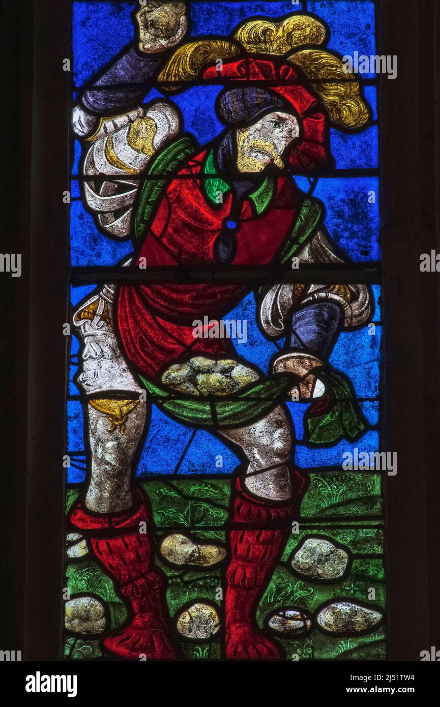 An executioner in 16th century costume hurls rocks at the first Christian martyr, Saint Stephen, in a vivid detail of early 1500s stained glass in the Église Saint-Rémi at Ceffonds, in the Champagne region of northeast France.  The colours are typical of Renaissance glass made in the workshops at Troyes, the historic regional capital. Stock Photo