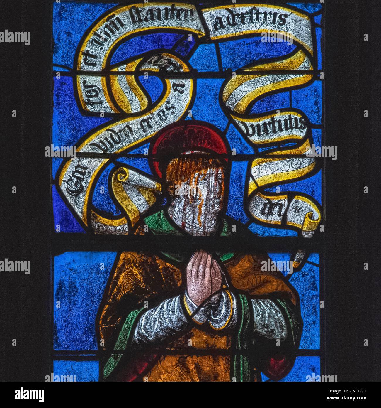 Stoical in death: blood streams down the face of Christianity's first martyr, Saint Stephen, as he kneels in prayer waiting to die under a barrage of rocks and stones: square detail of central panel in window of early 1500s stained glass in the Église Saint-Rémi at Ceffonds, in the Champagne region of northeast France.  The window also depicts Stephen's two executioners. Stock Photo