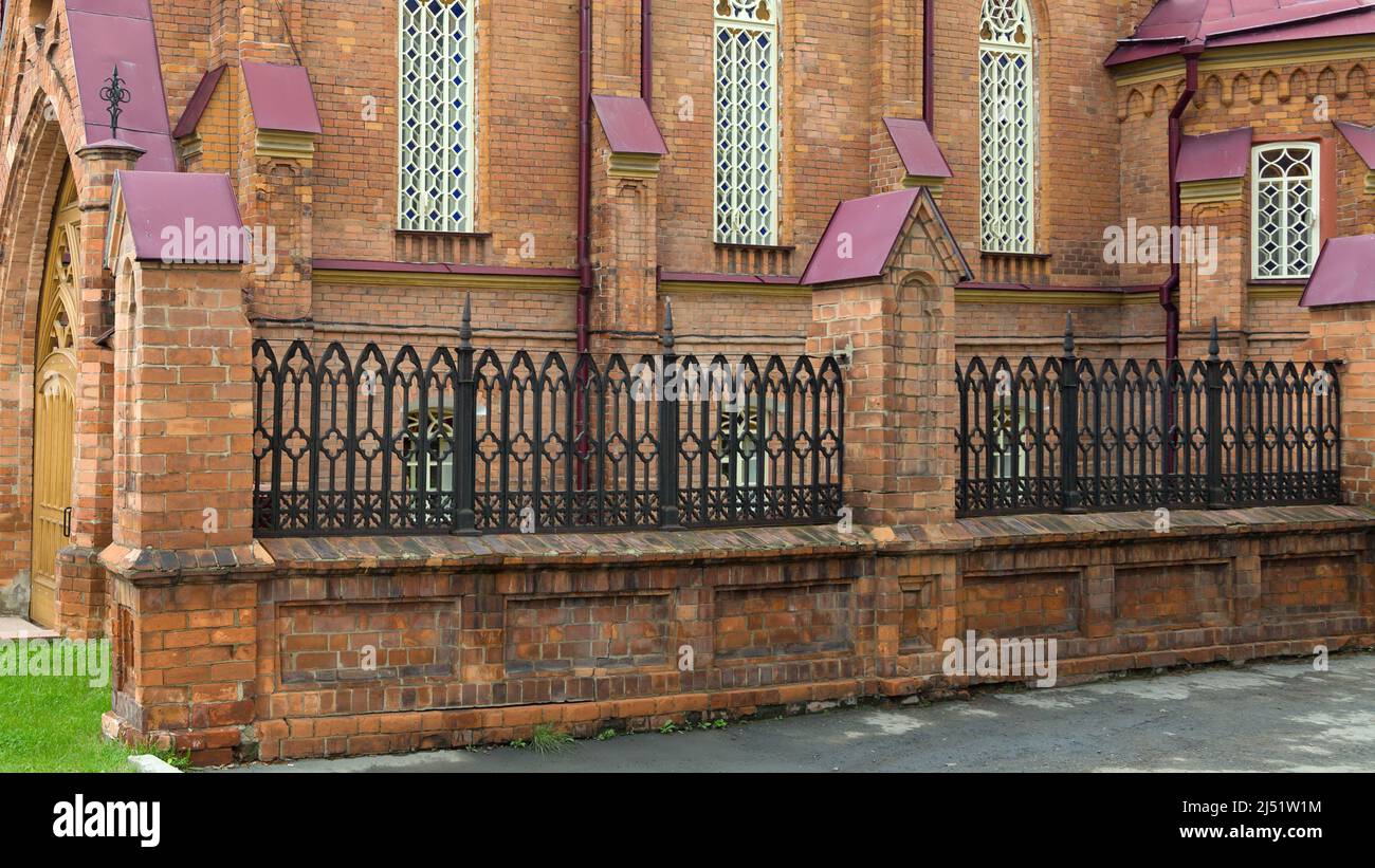 A high beautiful metal fence around old red brick building Stock Photo ...