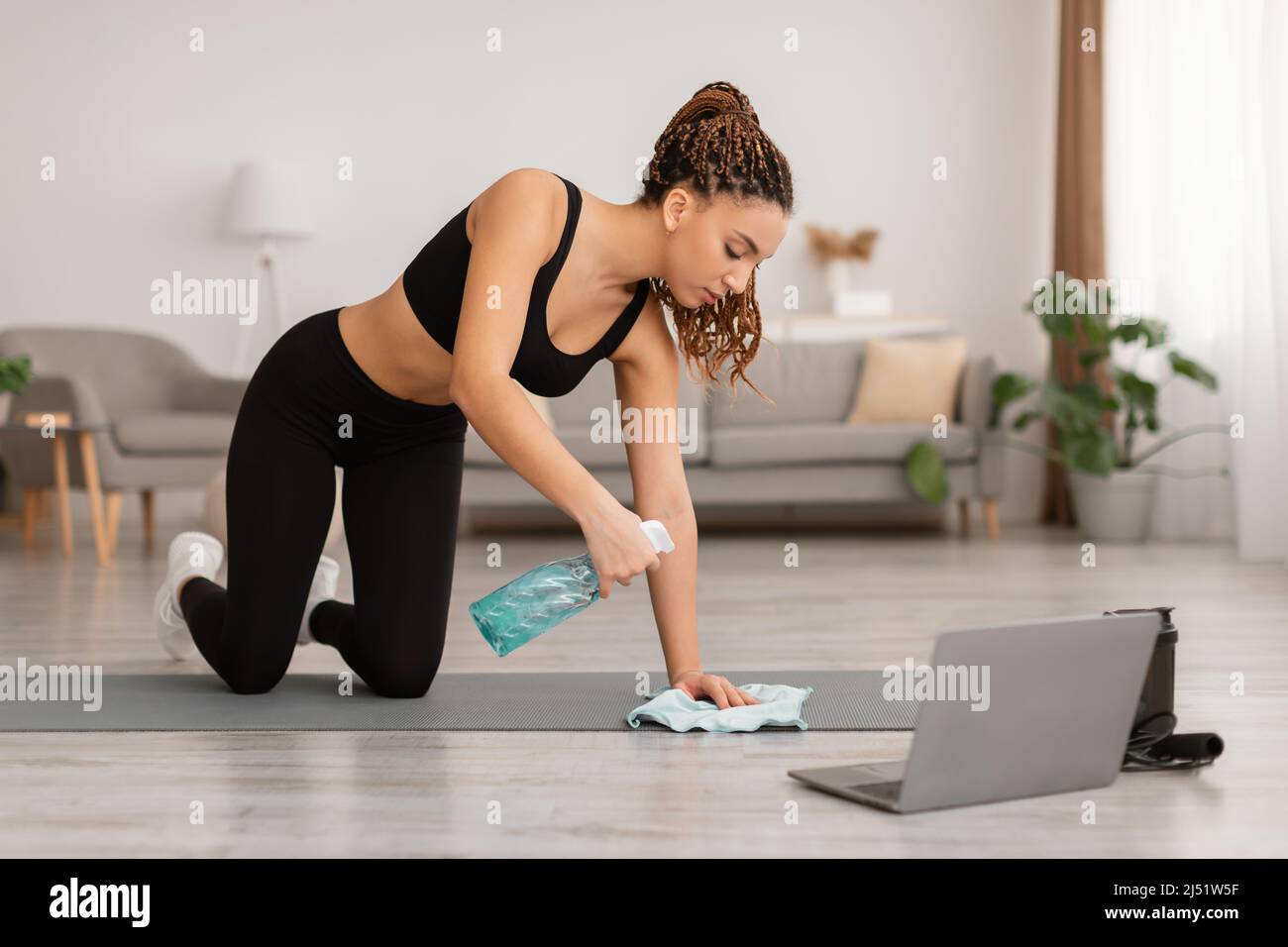 Black Female Cleaning Gymnastics Mat Using Detergent Before Workout