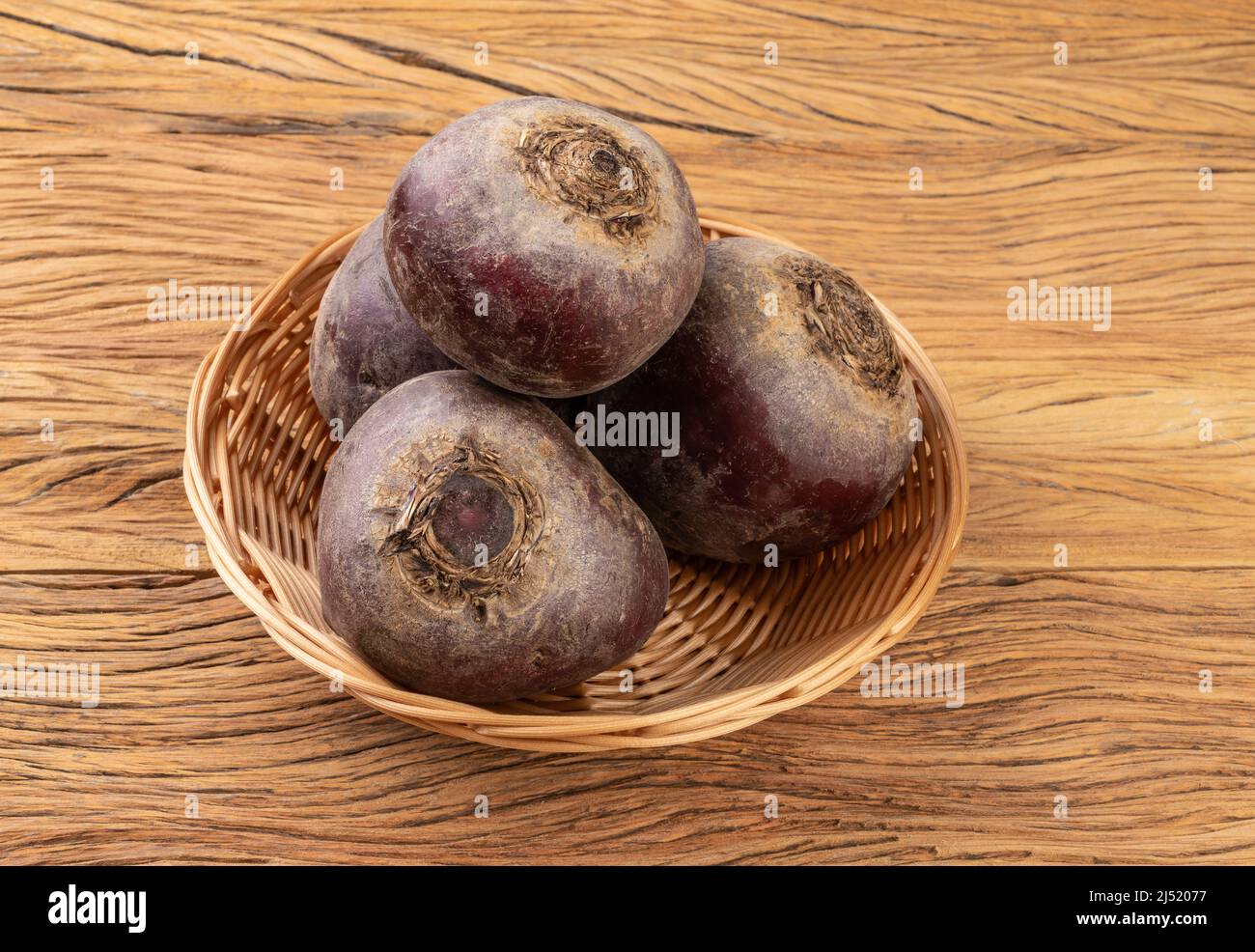 Raw beetroots in a basket over wooden table. Stock Photo