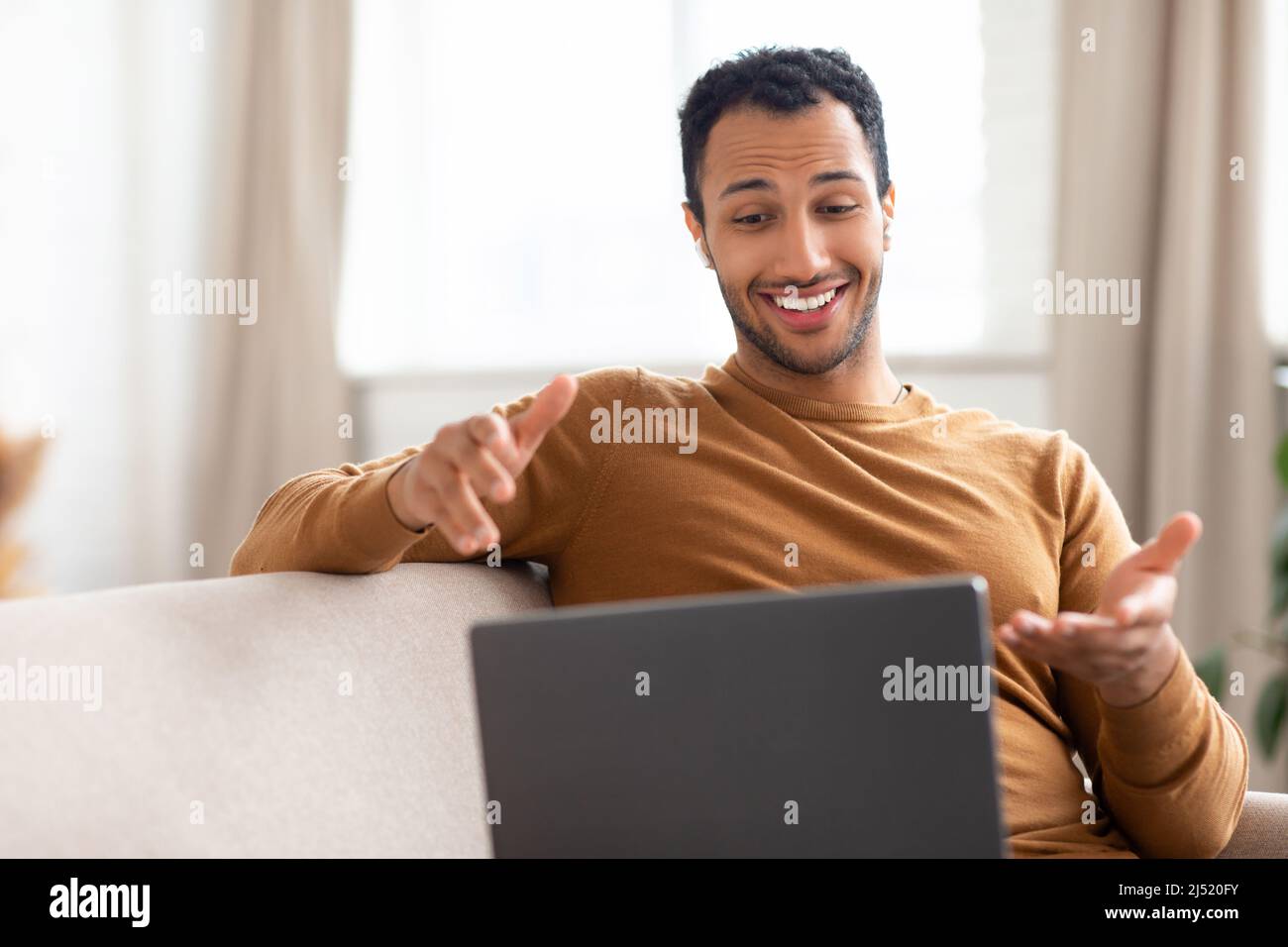 Arab guy making videocall using laptop wearing headphones Stock Photo