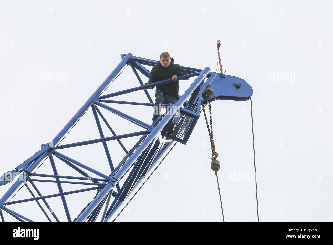 London, UK. 19th Apr, 2022. A man has climbed up the scaffolding and then  to the top of a tall construction crane at an office building construction  site at 2 Victoria Street.